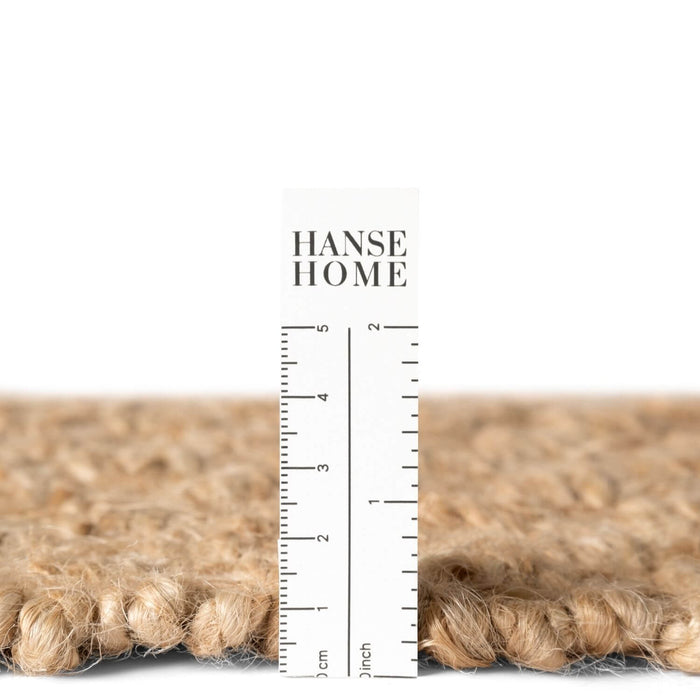 Close-up of a textured rug with a ruler and 'HANSE HOME' branding.