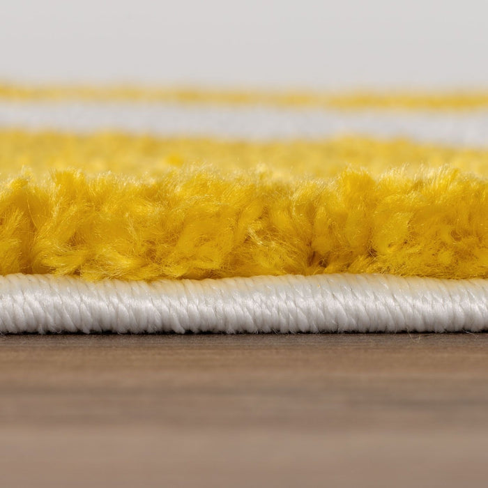 Close-up of yellow and white carpet fibers on a wooden floor.