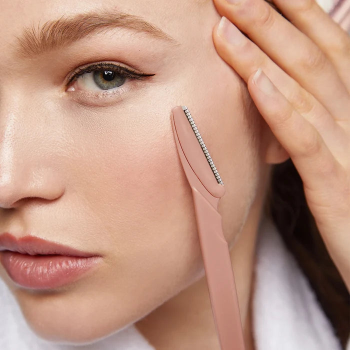 Woman using a pink skincare tool on her face
