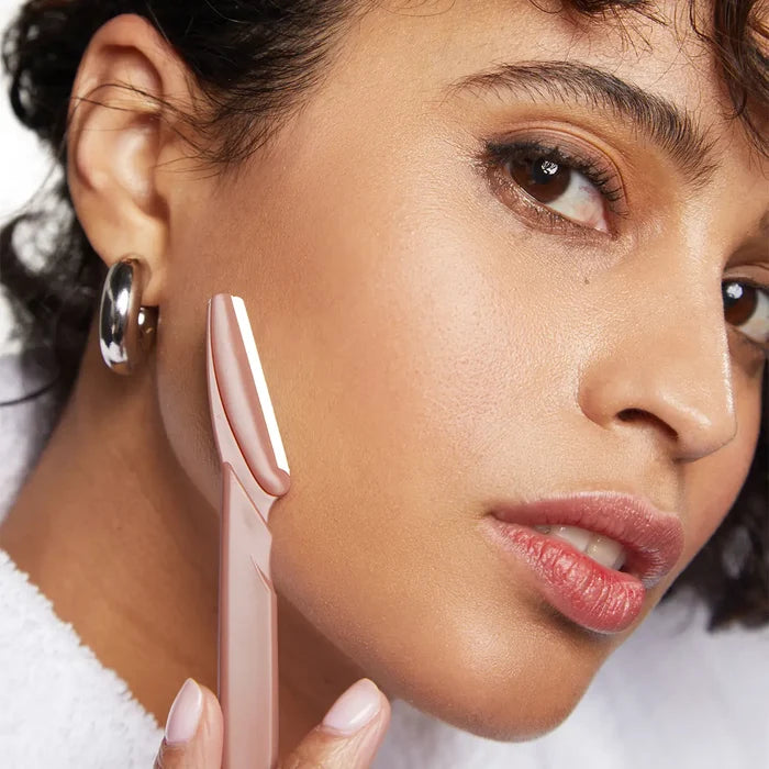 Close-up of a woman holding a pink makeup tool near her face.