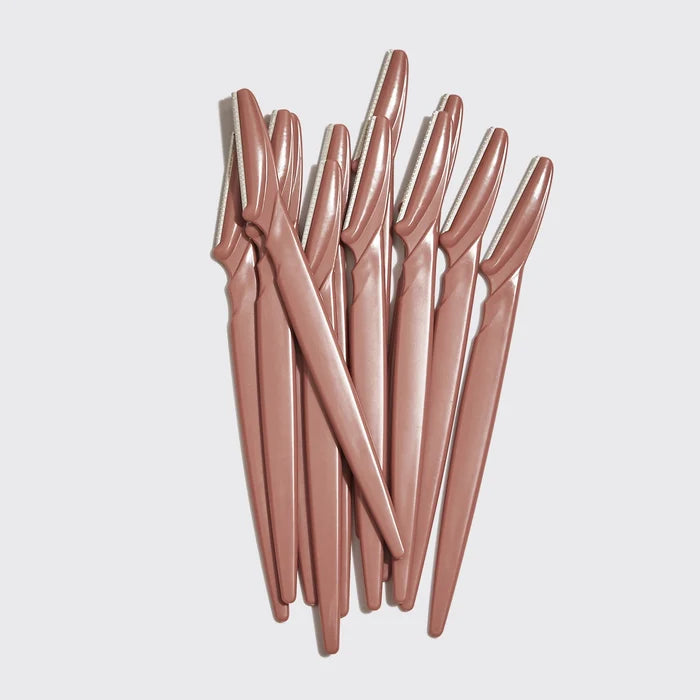 Set of rose gold eyebrow razors on a light gray background