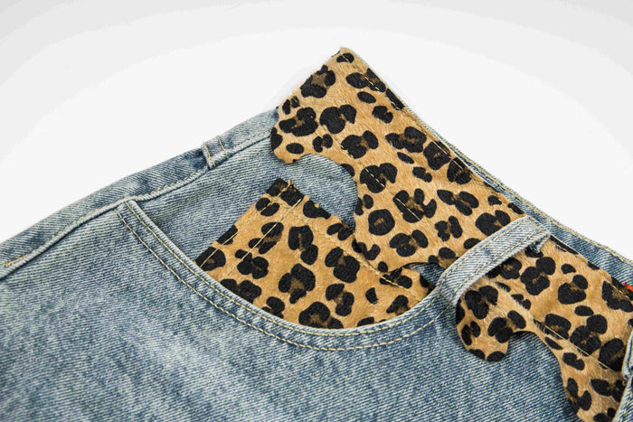 Close-up of waistband loops and leopard print patch detail on light wash denim shorts