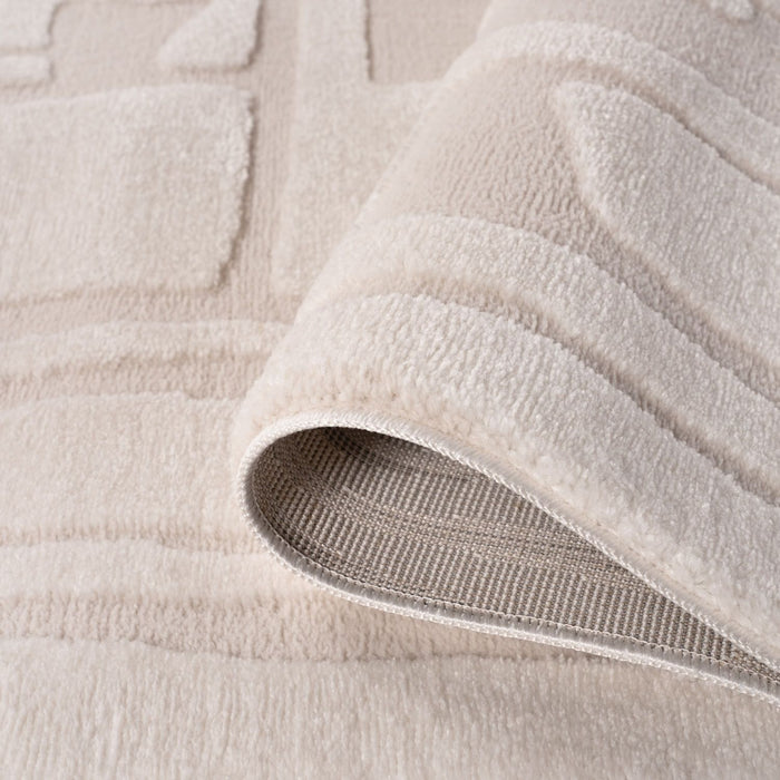 Close-up of a beige textured rug with a slight roll-up showing the underlayer.