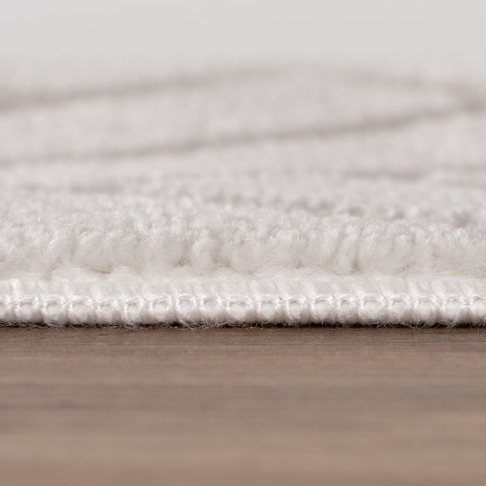 Close-up of a textured white rug on a wooden floor