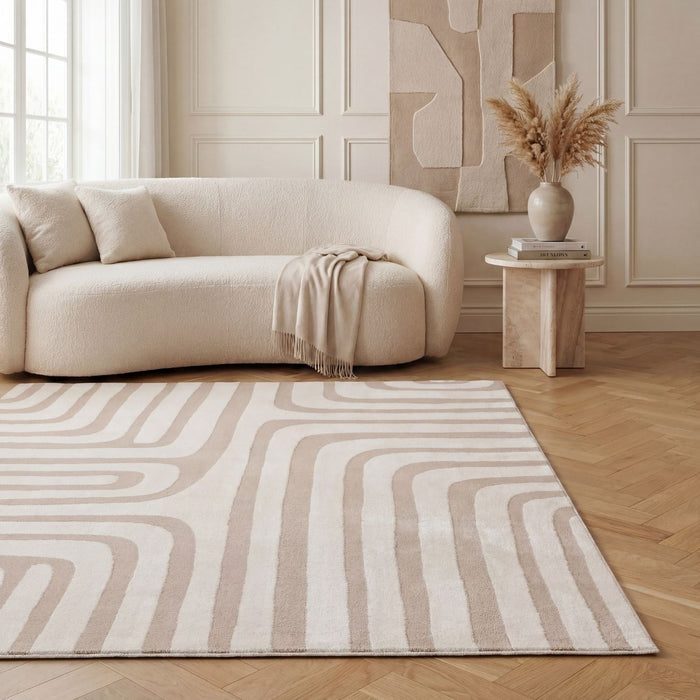 Beige and white patterned rug in a living room with a beige sofa and abstract wall art.