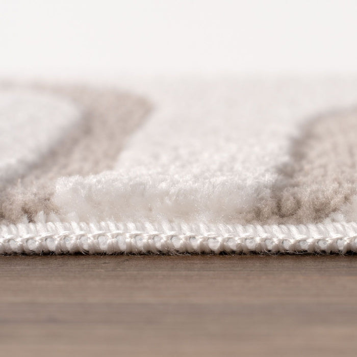 Close-up of a textured rug with a neutral color palette on a wooden floor.