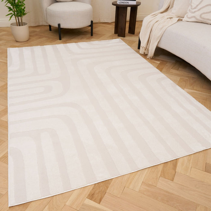 White rug on a wooden floor with a neutral-colored chair and plant in the background