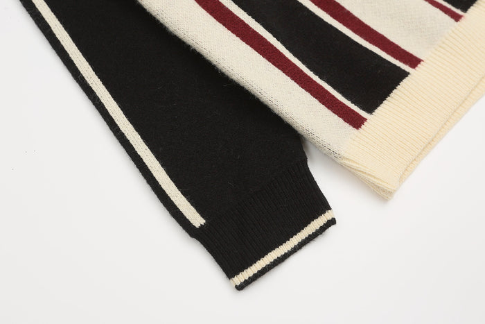 Close-up of sleeve cuff on black knit sweater with cream trim and burgundy stripe