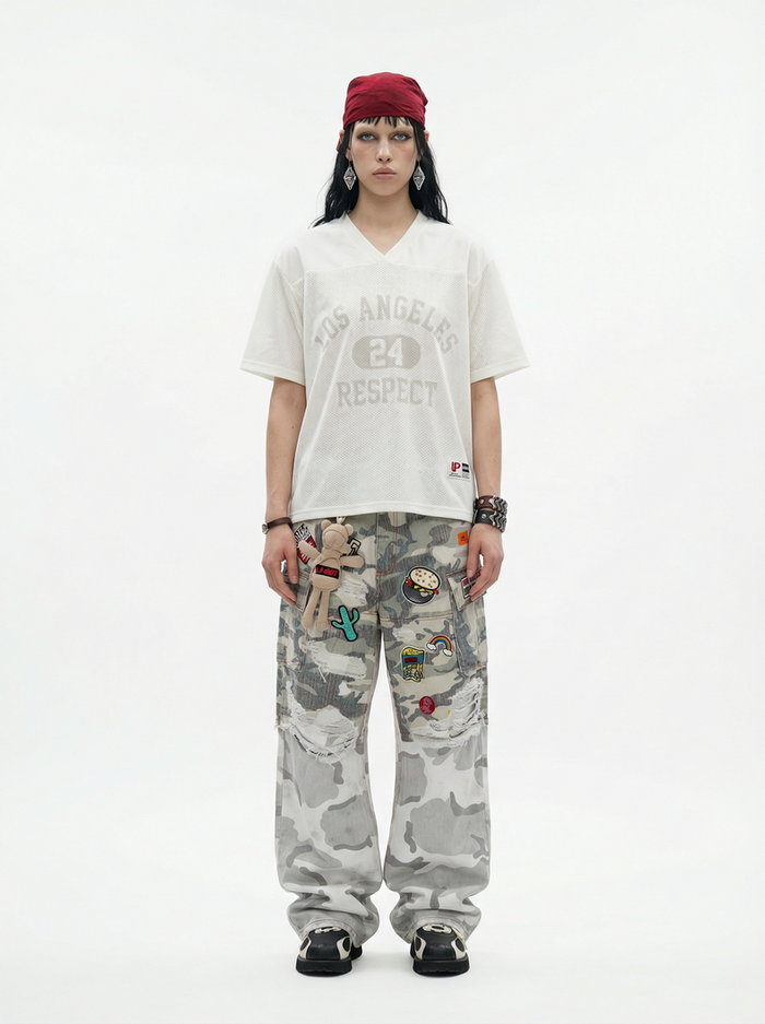 Model wearing an oversized white V-neck mesh tee with Los Angeles 24 Respect print, red headwrap, and camo cargo pants