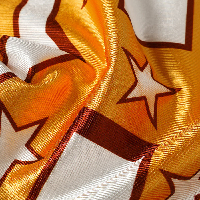 Close-up of a gold and white football jersey fabric with star and number graphics, showing a glossy streetwear texture