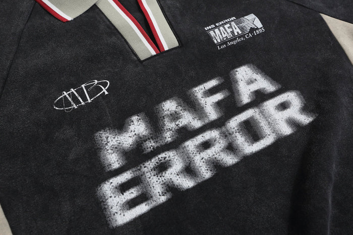 Close-up of black rugby sweatshirt front with spray-print graphics and striped polo collar