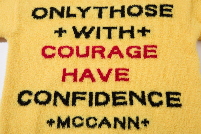 Front close-up of yellow fuzzy knit sweater with bold slogan text
