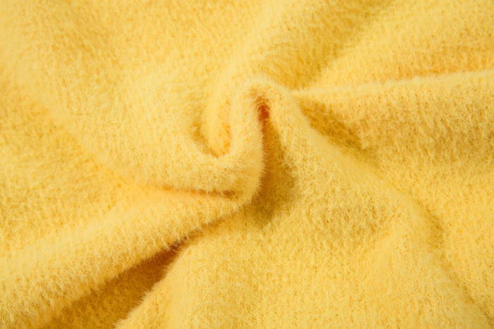 Close-up of yellow fuzzy knit sweater fabric and seams