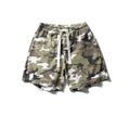Men's relaxed fit woodland camo shorts with elastic waistband and white cotton drawstring on a white background