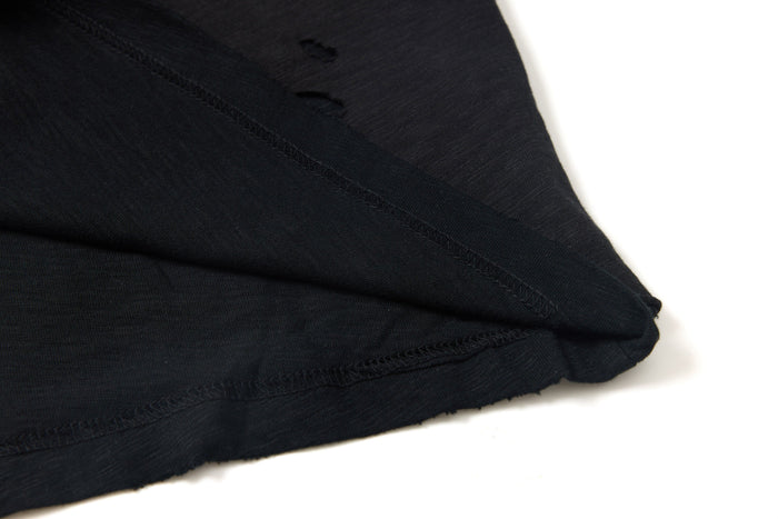 Close-up of a washed black distressed graphic tee with layered seams and raw hem detail