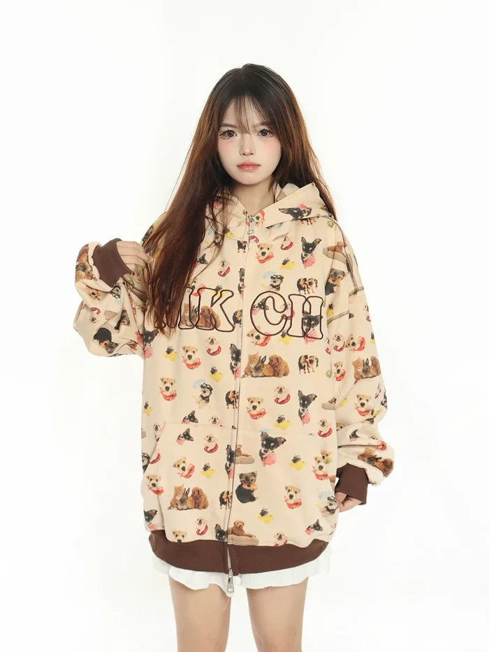 A person stands forward against a white backdrop, wearing an oversized beige hoodie adorned with puppy illustrations and the word "Chicago." The hood is up, hands in pockets. This Seakoff MKCH Dog Print Hoodie is a cute and quirky fashion statement, adding a fun touch.