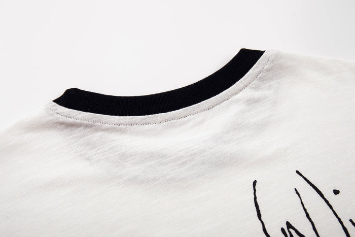 Close-up of a white graphic T-shirt with black ribbed collar and abstract horse design detail