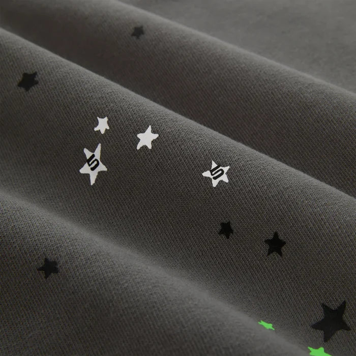 Close-up of heavyweight 440GSM cotton fleece with black, white, and green star patterns and stylized S symbols, evoking classic streetwear—reminiscent of the Sp5der “P!nk! Hares the Slime” Olive Green Spider-Web Pullover Hoodie.