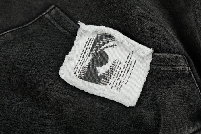 Close-up of frayed white patch with black graphic print on black hoodie