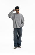 Gray oversized crewneck sweatshirt worn front view with hand raised to sunglasses
