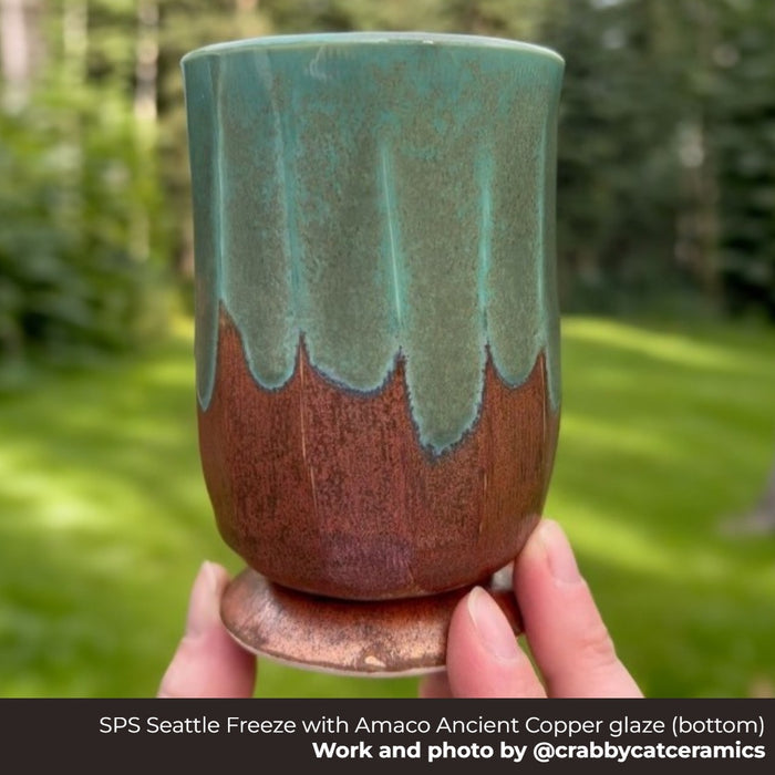 Footed tumbler in Seattle Freeze clay, Amaco Ancient Copper glaze below a dripping green glaze, held outdoors