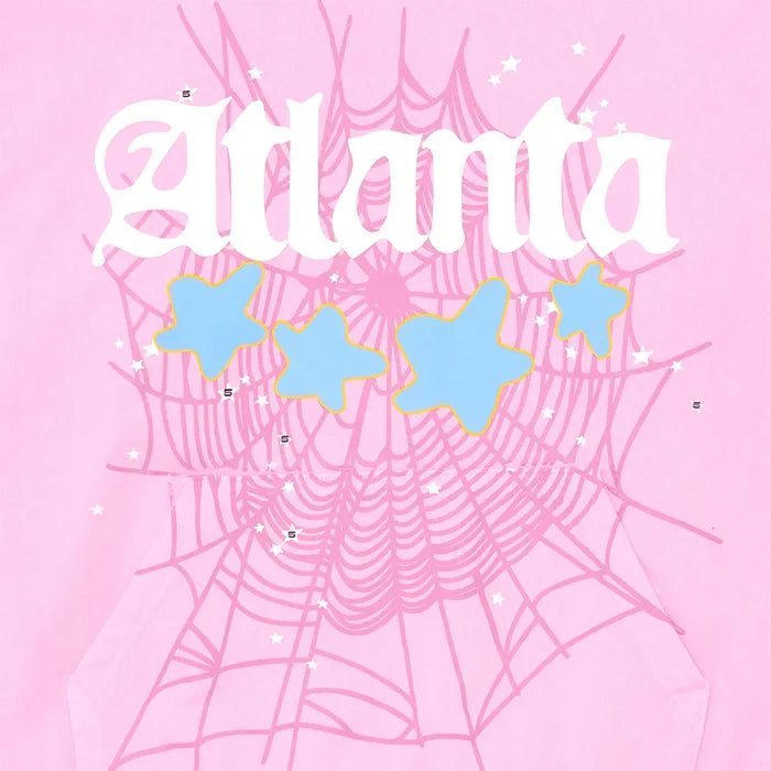 The image features “Atlanta” in white, stylized text on pink with a big spider web, blue stars with yellow outlines, and small white stars—matching the bold Y2K style of the Sp5der Atlanta Hoodie – Pink 440GSM Heavyweight Pullover.