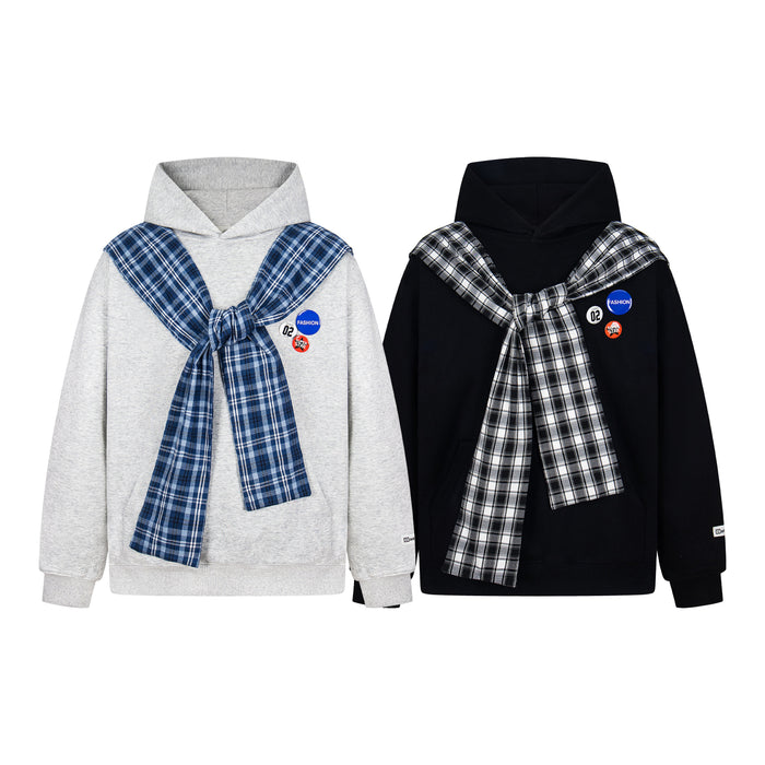 Grey hoodie with attached blue plaid scarf knotted at chest and decorative badge pins on white background