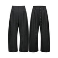Dark charcoal wide-leg pleated pants with asymmetric button front closure, shown front and back view on white background