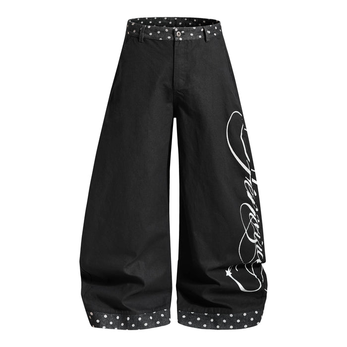 Black wide-leg denim jeans with white script print and polka dot waistband, front view