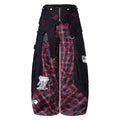 Front view of black wide-leg cargo pants with red plaid paneling and stitched graphic details