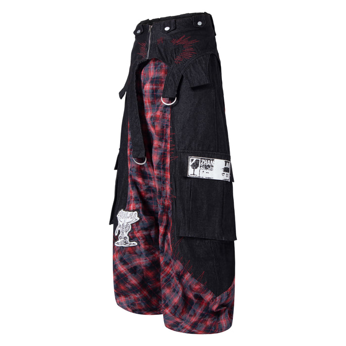 Side view of black cargo pants with red plaid inset panels, flap pockets, and metal ring detail