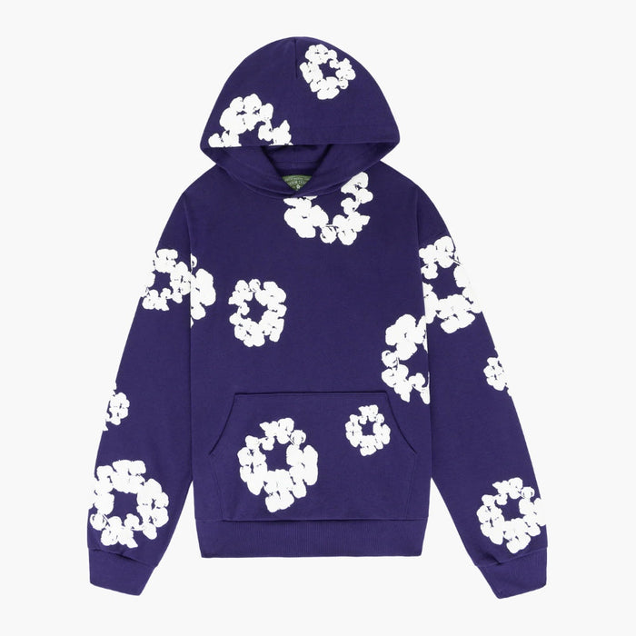 The Purple “Cotton Wreath” Denim Tears Hoodie is a streetwear pullover with a front pocket, featuring large white floral prints on purple fabric, inspired by the iconic Denim Tears style.