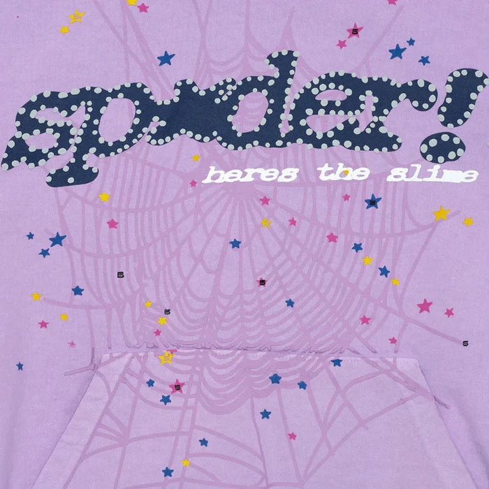 The Sp5der “Hares the Slime” Hoodie is a lavender purple 440GSM heavyweight pullover featuring bold dotted “spider!” text, “heres the slime” in white, a faint spiderweb with colorful stars, and a classic streetwear pocket.