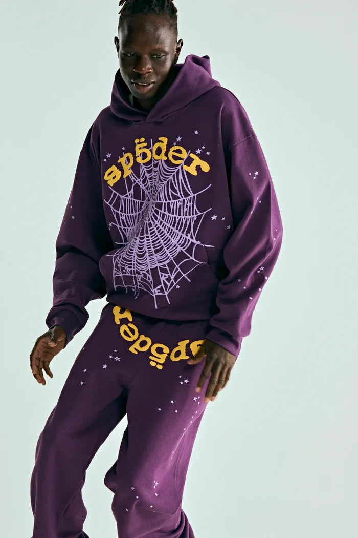 Wearing the Sp5der Web Hoodie – Deep Purple & Yellow 440GSM Heavyweight Oversized Streetwear Pullover, paired with matching sweatpants featuring yellow text and white spiderwebs, embodying luxury street style against a plain light background.