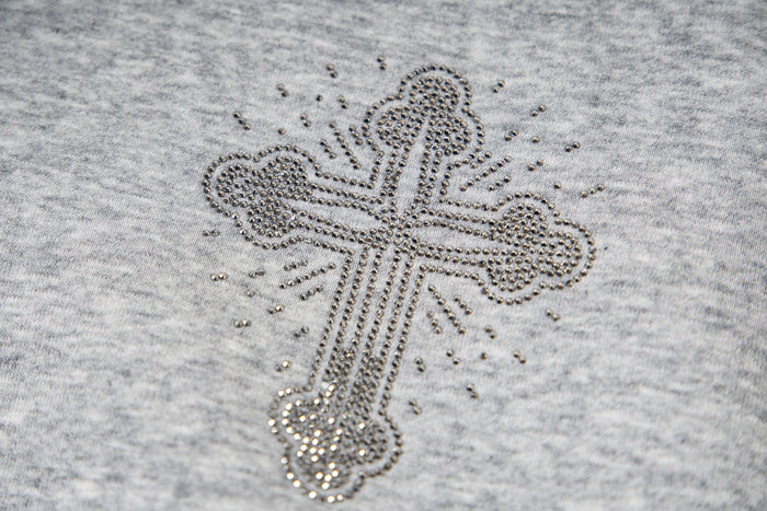 Close-up of rhinestone cross graphic on light gray fleece hoodie front