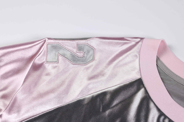 Metallic pink oversized varsity jersey tee with silver number patch and ribbed collar