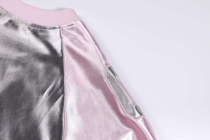 Close-up of a metallic pink and silver oversized varsity jersey tee with satin finish and shoulder detail
