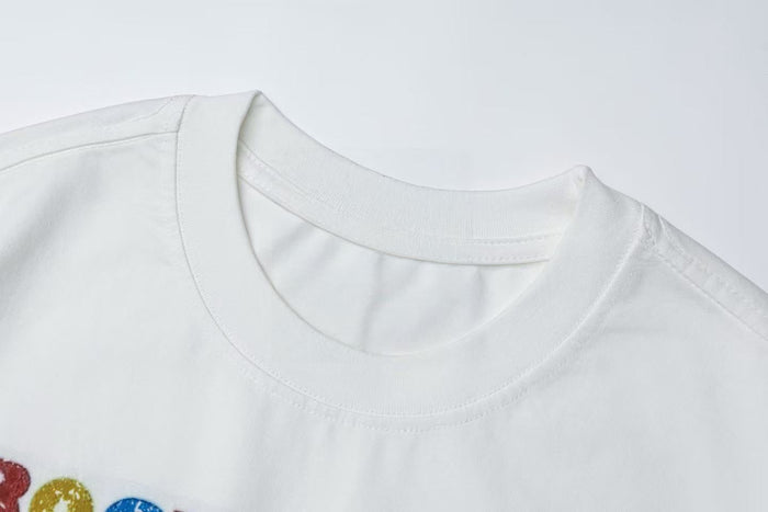 White graphic tee with a vintage rock collage print and ribbed crew neck detail