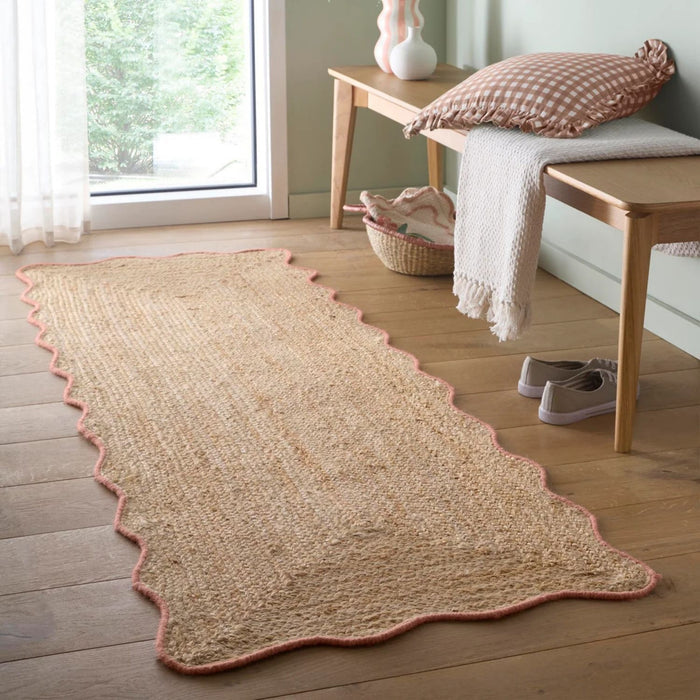 Beige woven rug on a wooden floor with a bench and window in the background