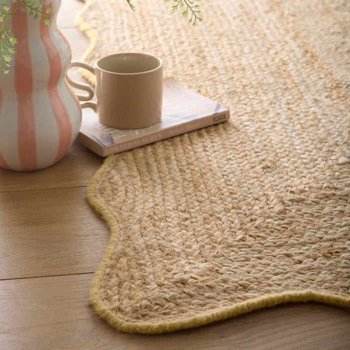 Natural woven rug on a wooden floor with a cup and vase.