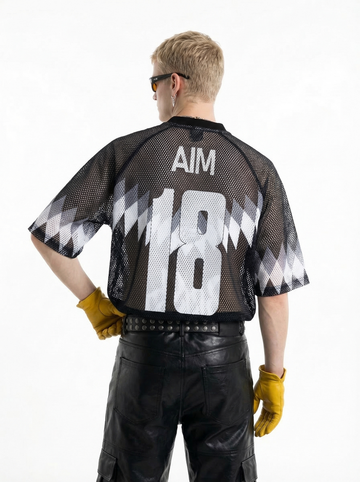 Black mesh soccer jersey with AIM 18 print, worn with black leather pants and yellow gloves, back view