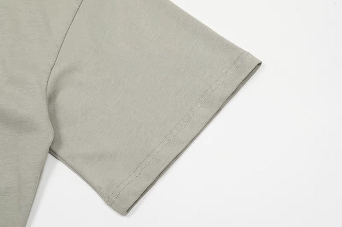 Light gray cotton tee sleeve with subtle asymmetric seam and clean minimalist hem detail