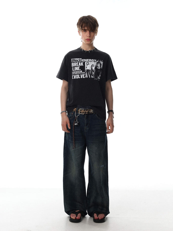 Black vintage washed graphic T-shirt with punk-style print, worn with loose dark jeans and a leopard belt on a model