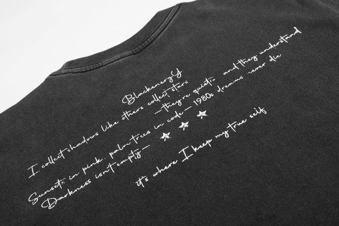 Black vintage washed graphic T-shirt with handwritten white text and star accents on the back neckline