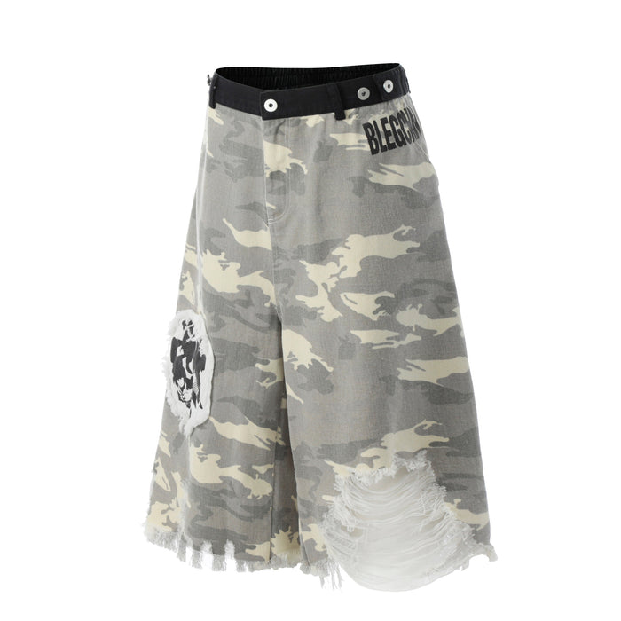 Front angled view of gray camo jorts showing black waist trim, printed logo, and distressed patch