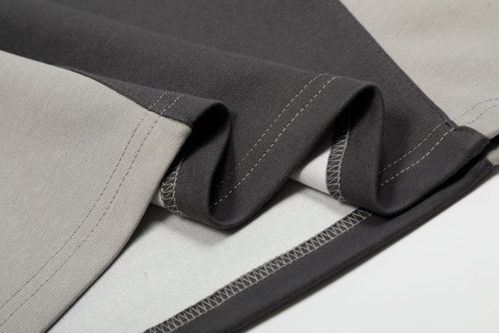 Close-up of a black, white, and gray color block cotton tee with visible contrast stitching and folded fabric texture