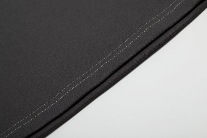 Close-up of black cotton tee fabric with contrast double stitching along the hem