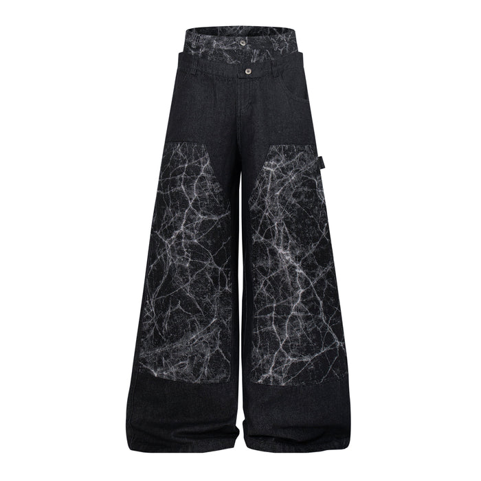 Front view of black wide-leg denim pants with cracked panel detailing and high waist