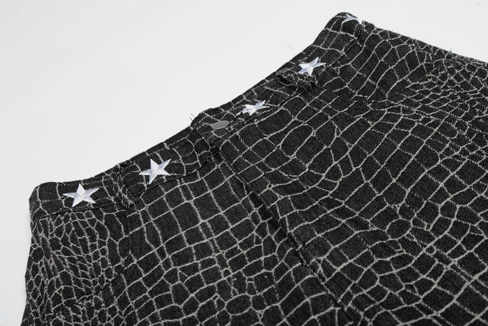 Close-up of black pants waistband with star embroidery and button detail