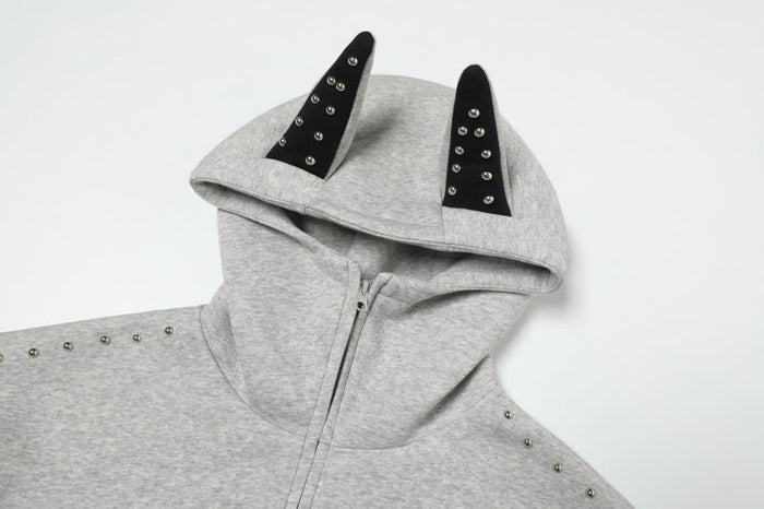 Close-up of grey hoodie hood with black devil horns and metal studs